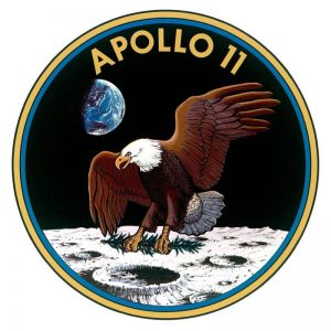 Apollo 11 mission patch showing a bald eagle landing on the Moon with an olive branch in its talons, Earth visible in the background, and APOLLO 11 at the top in yellow letters.