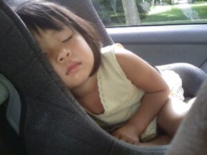 A young child sleeping in a car seat.