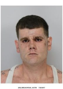 A man with short dark hair, thick eyebrows, and a serious expression wearing a white tank top stands against a plain background. The image appears to be a mug shot, dated 7/20/2017.