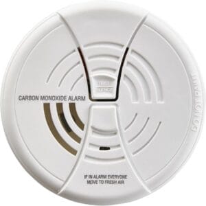 A round white carbon monoxide alarm with vents, a central “Test/Silence” button, and text reading “CARBON MONOXIDE ALARM” and “IF IN ALARM EVERYONE MOVE TO FRESH AIR.”