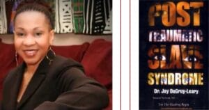 A woman with braided hair smiles and sits on a red couch, wearing a black top and hoop earrings. Next to her is the book cover for Post Traumatic Slave Syndrome by Dr. Joy DeGruy-Leary.