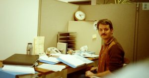 Me sitting at my desk during my first week on the job at JPL. My desk has many documents for me to review, but I don't have a computer yet.
