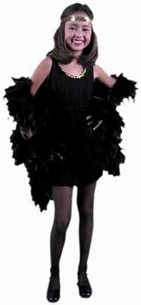 A young girl dressed in a 1920s-style flapper costume with a black dress, fishnet stockings, black shoes, feathered boa, and a headband, smiling against a plain white background.