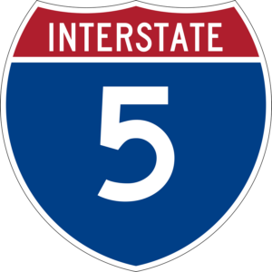 Interstate 5 shield sign featuring a red upper section labeled "INTERSTATE" and a large white number 5 centered on a blue background below.