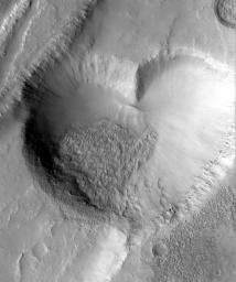 A heart-shaped landform on a rocky, cratered surface, captured in a grayscale image showing varying textures and elevations. It's a photo from Mars.