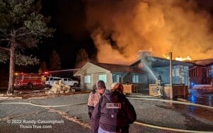 Firefighters working in the background as the two LEOs speak in the foreground.